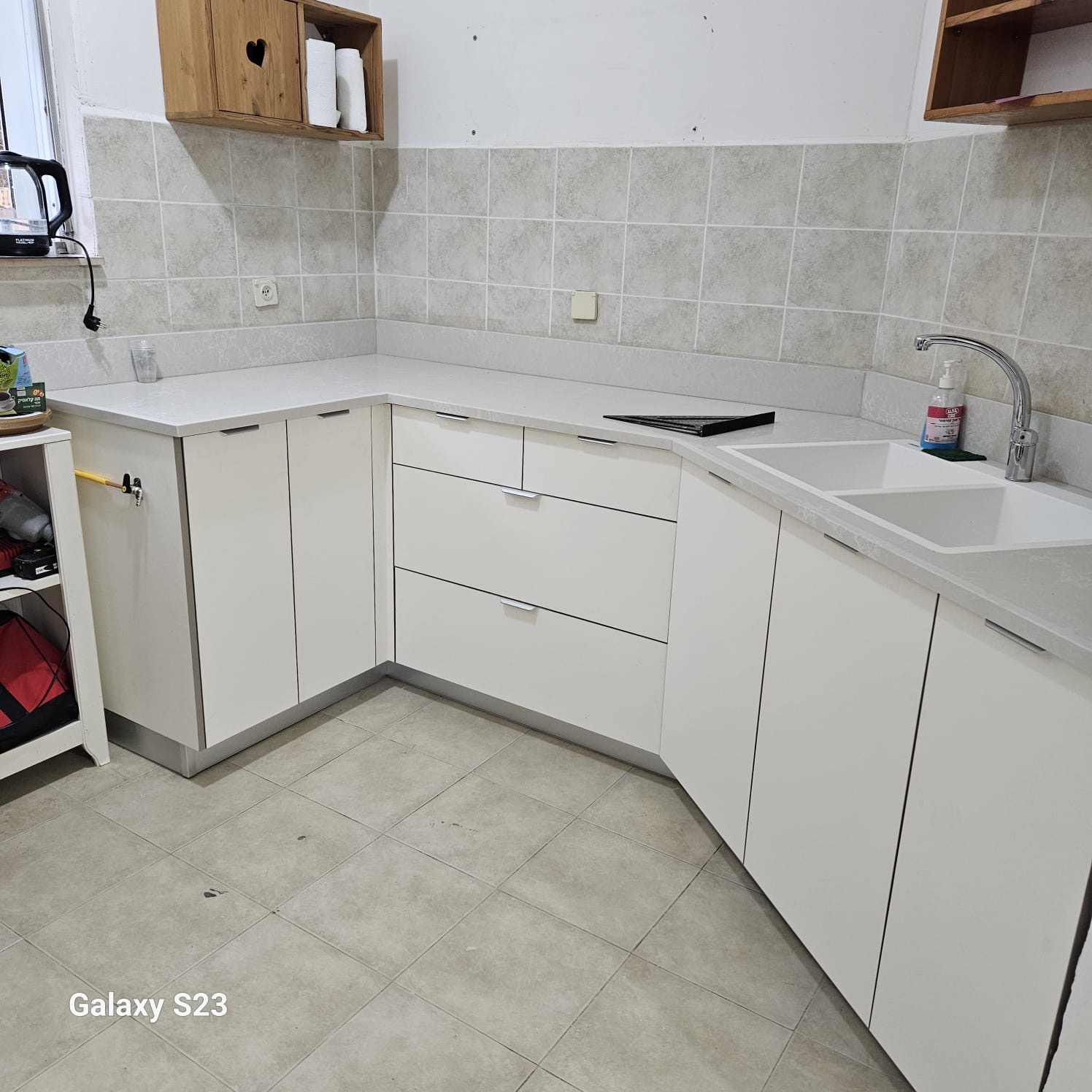 מטבח לבן בצורת ר' עם משטח קוורץ אפור בהיר ומדפי עץ אלון עליונים – פרויקט מטבח קלאסי