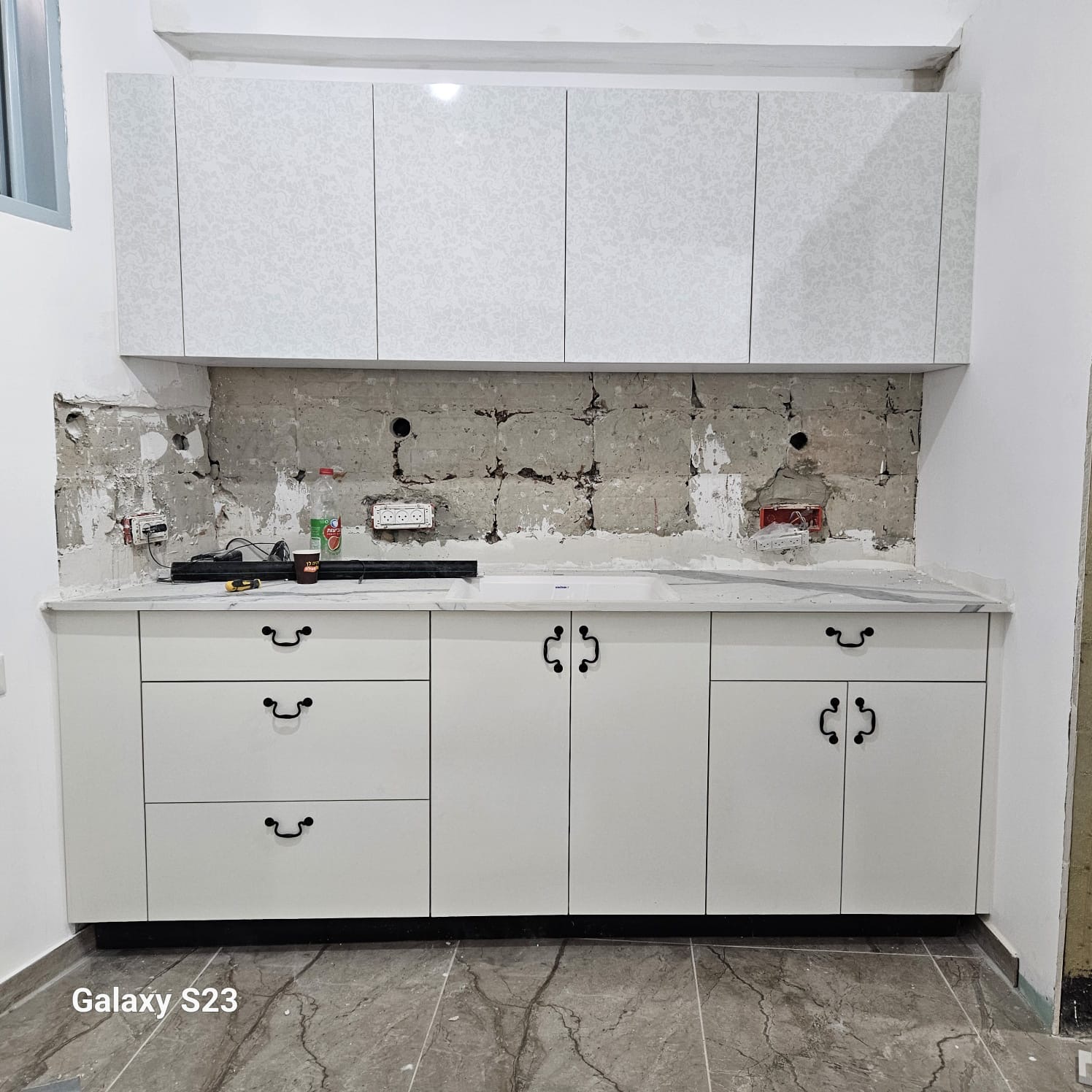 מטבח לבן קלאסי עם ידיות שחורות בסגנון וינטג' ומשטח שיש קלקטה – שילוב מסורתי ומודרני